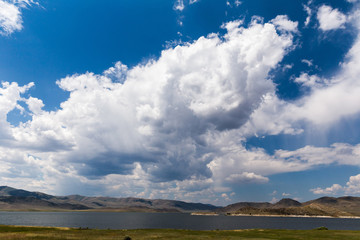 Fototapeta premium Cumulus Clouds and Blue Sky Over Lake