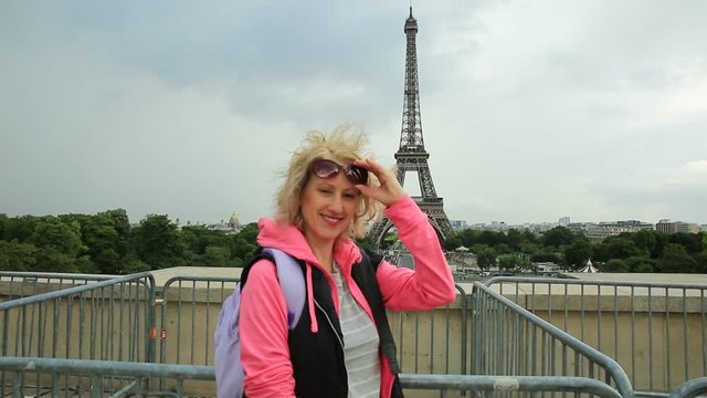 Smiling tourist woman in Paris with at Place du Trocadero. Traveler tourist woman in French capital, Europe. Eiffel Tower and Paris skyline on background. Travel and tourism concept.
