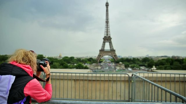 Professional photographer with camera on Place du Trocadero takes shot of Tour Eiffel. Traveler woman in Paris, France, Europe. Eiffel Tower on blurred background. Travel and tourism concept