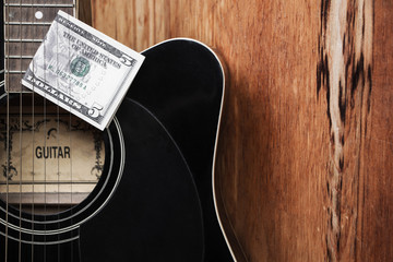 Black guitar close-up with five dollars