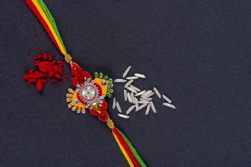 Raksha Bandhan : Rakhi with rice grains and kumkum on black background, Traditional Indian wrist band which is a symbol of love between Brothers and Sisters.
