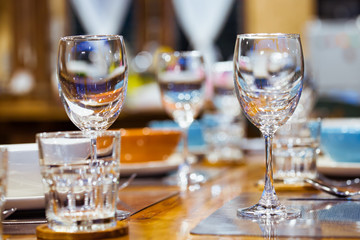 Close-up empty wine glasses on wooden table. Part of dining table interior