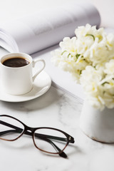 White kitchen benchtop, flowers, coffee and reading glasses