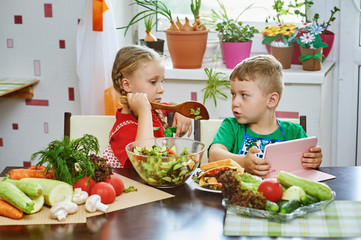 Children prepare salad vegetables . Happy kids in the kitchen . The concept of a healthy wholesome...