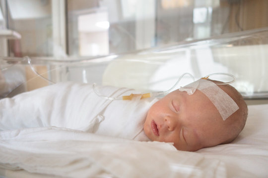 Newborn baby sleeping on a drip in a hospital
