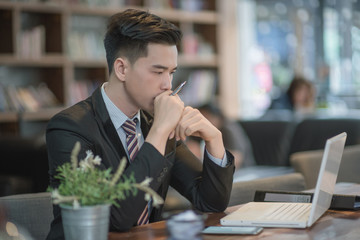 Young attractive Asian business man sleeping, drowsing or taking a nap at her desk, Tired business man accountant with bills and paper folders in office, tired young business man with laptop.