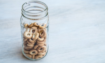 Mini bagels Russian baranka in glass jar on white gray wood background