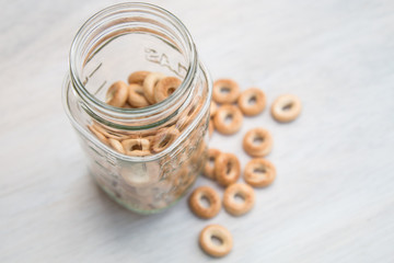 Mini bagels Russian baranka in glass jar on white gray wood background