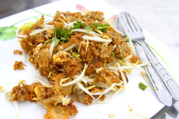 Oysters fried in egg batter in a white dish with spoon and mug