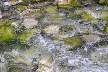 Mossy rocks in stream with clean flowing water.