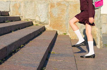 girl in school uniform with a backpack walking on steps