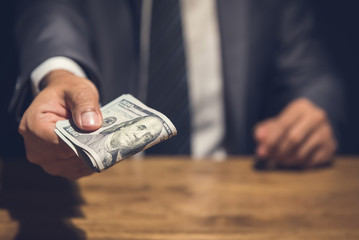 Dishonest businessman secretly giving away money in the dark
