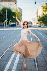 Obraz premium Ballerina in leotard and skirt and ballet shoes dancing on the street, jumps and bends 