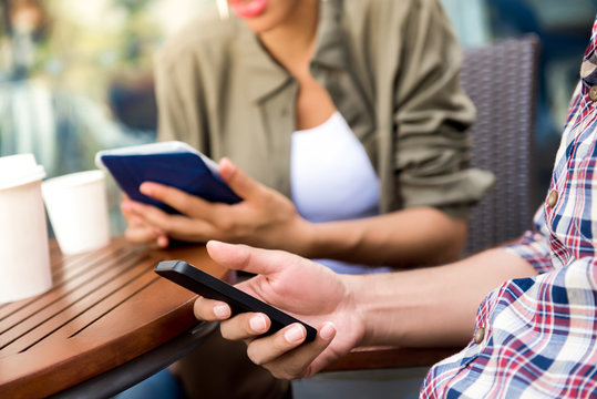 People concentrating on using mobile phone and tablet computer while sitting in coffee shop