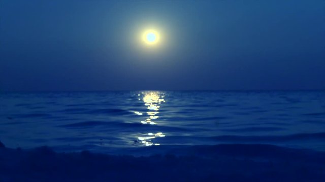 Night scene with full moon shining and reflecting on water. Sea, ocean beach at night. Slow motion 240 fps. 4K UHD video 3840x2160