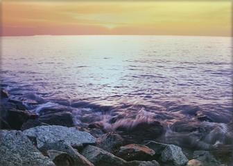 Colourful sunset over waves crashing on rocks
