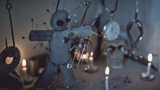 the voodoo doll swinging on the hook over the ritual table