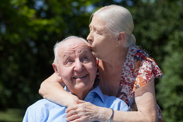 alte Frau küsst ihren Ehemann auf die Stirn