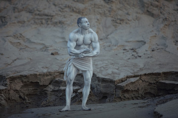 Fototapeta na wymiar Male bodybuilder posing as a statue is made of stone.