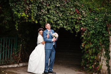 Attractive young wedding couple enjoying each other's company outdoor next to the ivy wall.