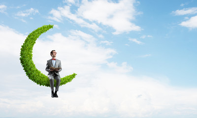 Young businessman or student on moon in sky studying the science