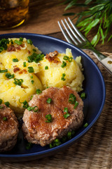 Meatballs served with boiled potatoes on a plate.
