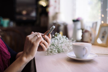 Girl freelancer using smartphone in cafe. Woman drink coffee and send chatting on phone. Close up