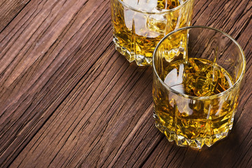 Whisky with ice in two glasses on a wooden background. Copy space. Food background