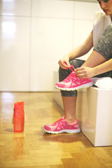 Sportswoman tying laces on sneakers. Close up of woman hands tying the laces on her running sneakers.