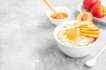 Oatmeal with nectarine and honey on a gray background. Copy space. Food background
