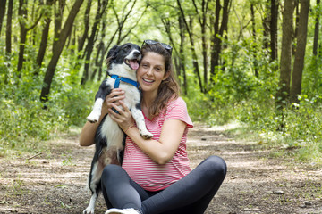 happy pregnant woman hugging  her border collie dog in the summer  park 