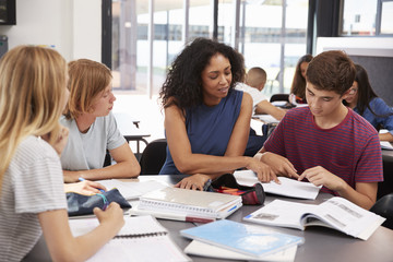 Teacher studying school books in class with high school kids