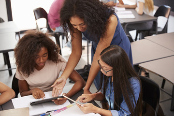 Teacher helping students with technology, high angle