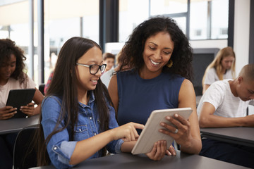 Teacher helping teenage schoolgirl with tablet computer - Powered by Adobe