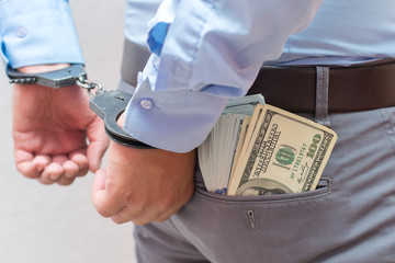 Corruption and bribery concept - arrested official with money in hands on white background