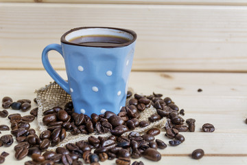 blue coffee cup with white dots and coffee beans on a wooden background