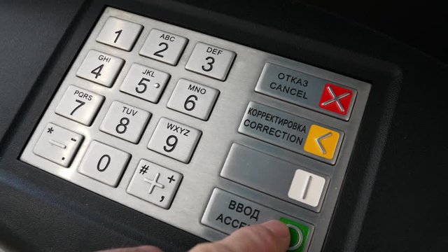 A set of pin code in the ATM. A person enters their password on the ATM keyboard.