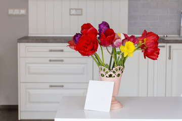 bouquet of red  tulips and narcissus with empty message card 