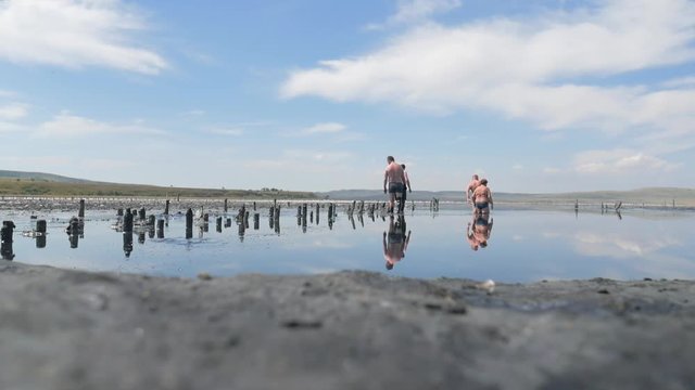 Unrecognized Tourists Walking into Lake With Black Mud and Sea Salt. Crimea, Russia.