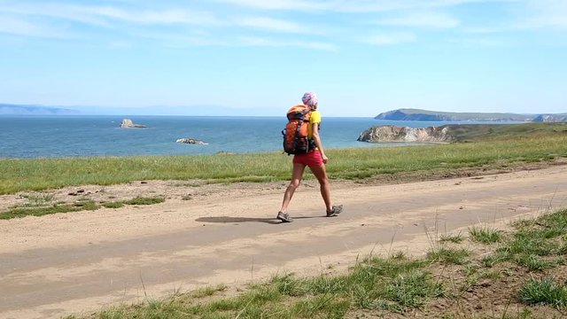 Woman hiker walking. Hiking girl walking alone in beautiful landscape nature. Caucasian girl living healthy lifestyle. Olkhon island, Lake Baikal, Russia
