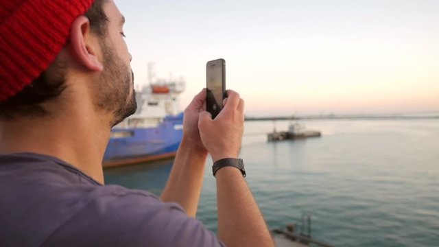 Young Man on a Ferry Taking Panorama Photo of Sea and Ships with Mobile Phone. HD Slowmotion. Crimea, Russia.