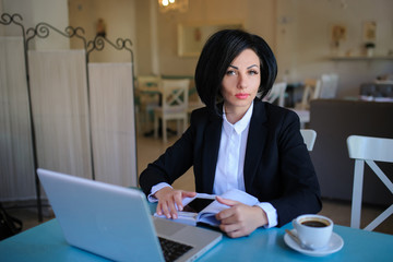 Fototapeta na wymiar business lady dressed in black suit working on a laptop