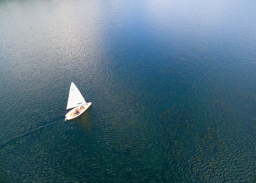White yacht on blue sea. Aerial view to sail boat. Summer activities from above.
