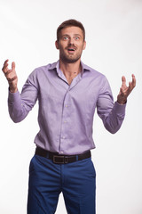 Young surprised man portrait of a confident businessman showing by hands on a gray background. Ideal for banners, registration forms, presentation, landings, presenting concept.