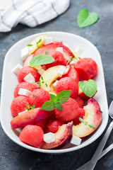 Summer watermelon salad with tofu, peach and mint on concrete, slate or stone background. Selective focus.