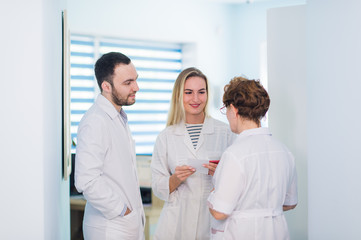 Fototapeta premium Mature doctor discussing with nurses in a hallway hospital. Doctor discussing patient case status with his medical staff after operation.