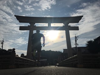 Silhouette of man running to Japanese Torii Gate in early morning
