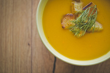 Pumpkin and carrot soup with crackers and parsley on wood background with Slices of bread
