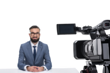 selective focus of male newscaster sitting in front of camera, isolated on white