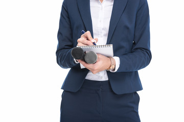 cropped view of female journalist in suit with microphones writing in notepad, isolated on white